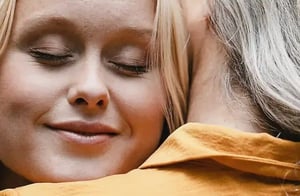 Junge Frau umarmt alte Frau